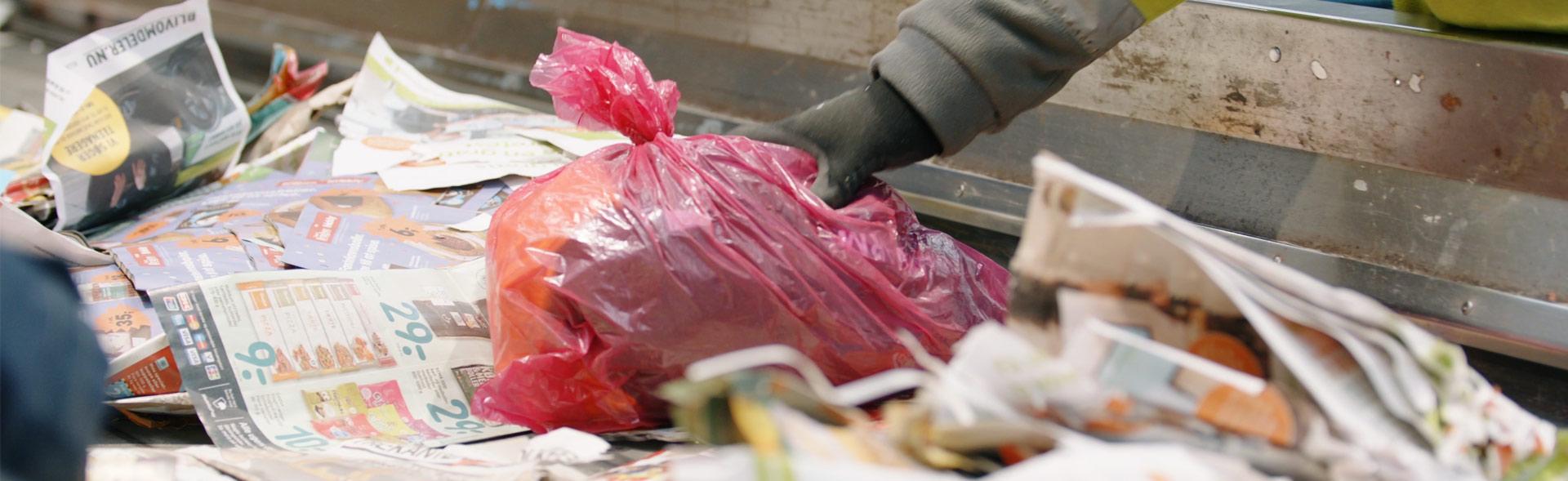 Rød pose med tekstilaffald bliver sorteret fra papir på sorteringsanlæg